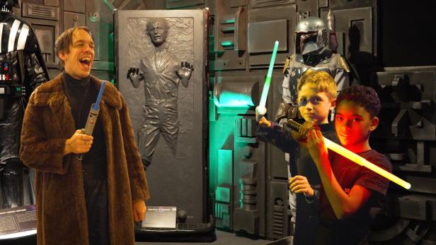 Star Wars Fans: Ein Erwachsener und zwei Kinder mit Leuchtschwertern 
