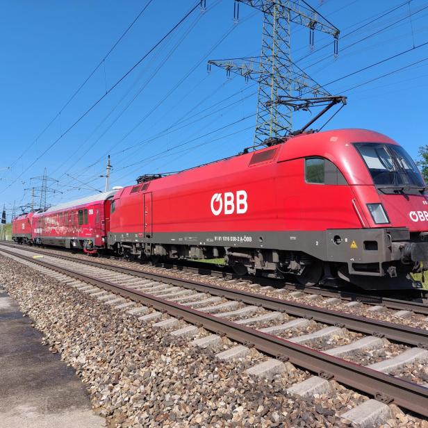 Ein roter ÖBB-Zug ist auf den Gleisen unterwegs.
